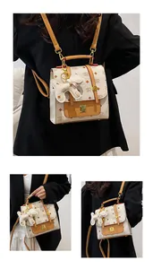 Detail of printed beige backpack with brown leather trim, metal NK logo, and dog charm