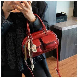 Detail of red patent leather pillow bag featuring dual front pockets and silver buckles
