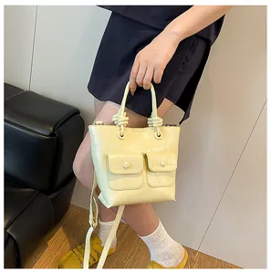 Detail of a beige croc-embossed handbag with knot handle design and dual front pockets