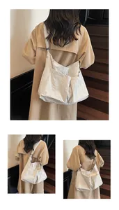 Detail of large beige crossbody bag with pleated texture and adjustable wide strap
