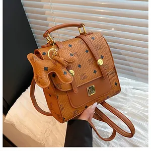 Detailed view of brown faux leather mini backpack with AK print and cute dog charm