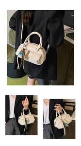 Detail view of beige Boston pillow bag with front double pockets and tassel accessories