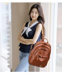 Detail of brown litchi leather backpack featuring golden kangaroo logo and zipper pockets
