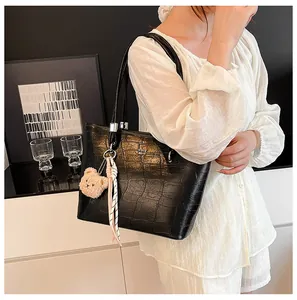 Détail du sac cabas noir motif crocodile avec breloque ours et ruban rayé décoratif