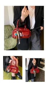 Detail of red leather Boston bag featuring decorative pockets and colorful bag charms