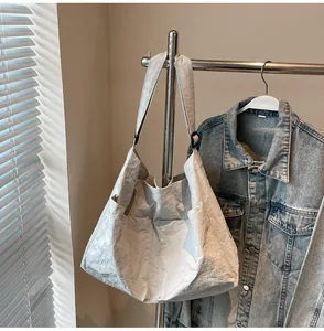 Detail of light grey pleated tote bag with large double pockets on a metal hanger
