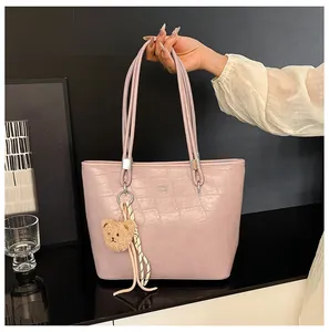Détail du sac cabas rose texture croco avec logo en métal et charm ours mignon