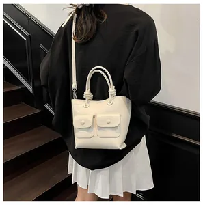 Detail of a minimalist white crossbody bag featuring crocodile texture and ring handle detail