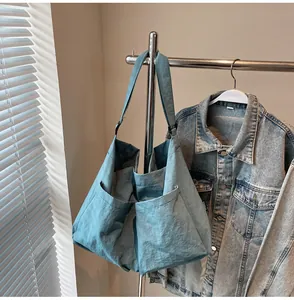 Light blue large capacity nylon tote bag with front pockets hanging on a metal hanger