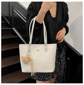 Détail du sac cabas blanc motif crocodile avec finitions argentées et breloque ours