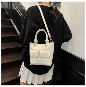 Detail of cream crocodile embossed handbag with knotted handle and double front flap pockets