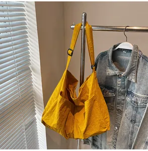 Detail of yellow nylon tote bag with adjustable shoulder strap and large front pockets