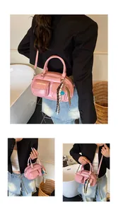Detailed close-up of pink glossy PU baguette bag with side pockets and beaded charms