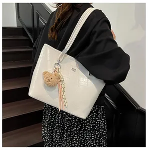 Détail du sac cabas blanc à motif crocodile avec breloque ours et foulard en soie