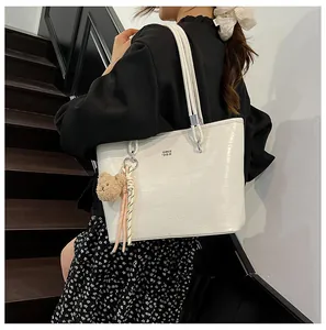 Vue détaillée de la texture crocodile blanche sur grand sac cabas avec bijou ours