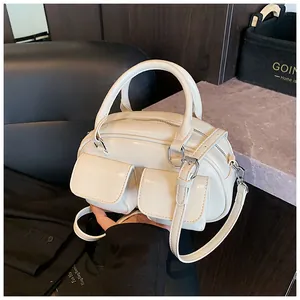 Close-up of cream white glossy pillow bag showing dual front pockets and silver hardware