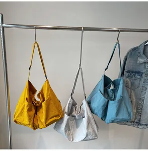 Detailed display of casual tote bags in yellow, grey, and blue on hangers with denim jacket