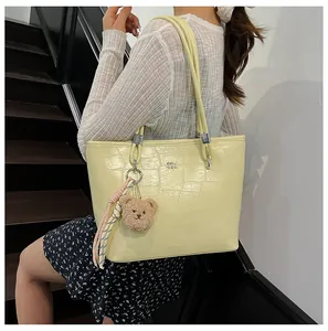 Détail d'un sac cabas crème à texture crocodile avec boucles argentées et breloque ours