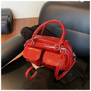 Detail view of red glossy patent leather pillow bag with dual front pockets and silver hardware