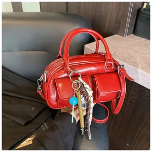 Detail of red glossy patent leather handbag with dual front pockets and colorful charms
