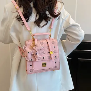Pink faux leather backpack with NK monogram pattern and cute dog charm shown on model
