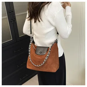 Brown faux suede tote bag with black leather flap and silver chain strap on model