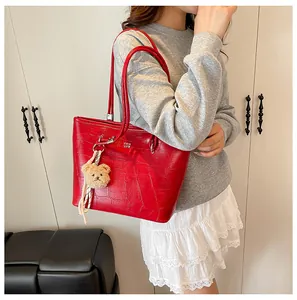 Détail du grand sac cabas rouge à motif crocodile avec charm d'ours en peluche doux