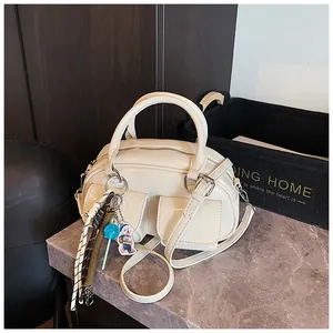 Close-up of cream glossy pillow bag with front flap pockets and colorful charm accents