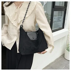 Detail of the suede textured body and leather flap on this black chain tote bag