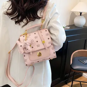Pink printed leather backpack with gold buckle and puppy charm shown on a model