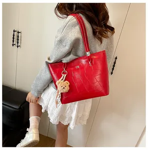 Détail du sac fourre-tout rouge à texture crocodile avec un ours en peluche et un foulard