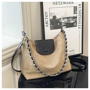 Detail of khaki suede and black leather tote bag with metal chain on display