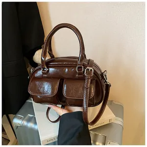 Detail of dark brown glossy Boston bag featuring double small front pockets and round handles