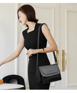 Detail of black crossbody bag with litchi texture and adjustable shoulder strap worn by model