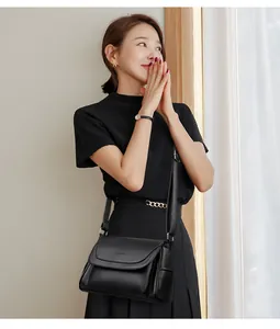 Detail of black leather crossbody bag with golden logo and adjustable shoulder strap