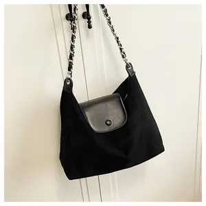 Detail of black tote bag featuring premium suede texture and silver chain strap