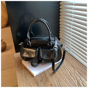 Detail of glossy black boston bag with front flap pockets and adjustable strap