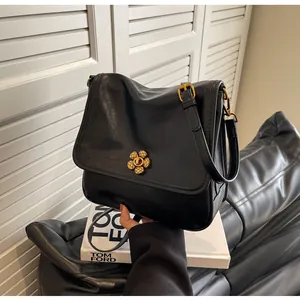 Close-up of a vintage black oil wax leather bag with an elegant golden flower lock