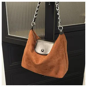 Detail of hobo bag with brown suede fabric, black leather flap and silver chain strap
