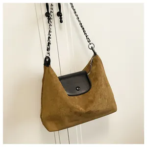 Detail of a brown suede shoulder bag with black leather flap and silver chain strap