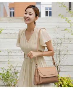 Detail of minimalist beige shoulder bag showing fine lychee texture and brand logo