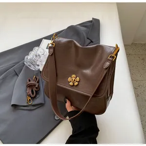Close-up of a retro brown leather shoulder bag featuring a gold floral clasp and strap