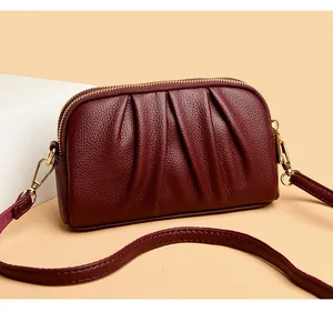 Close-up of wine red crossbody bag featuring litchi texture and double zipper detail