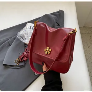 Detailed view of dark red vintage shoulder bag with floral metal lock and leather texture