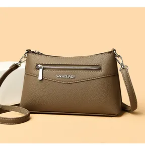 Dettaglio della borsa a tracolla in pelle marrone con zip argento e logo YAGELAIS