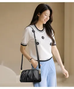 Detail of black pebbled leather crossbody bag with pleated cloud design and gold zipper