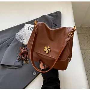 Close-up of caramel vintage crossbody bag with a bronze flower lock on a suit