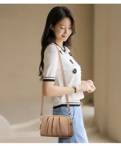 Detail of light brown pleated leather crossbody bag with golden hardware and adjustable strap