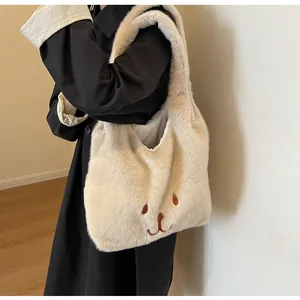 Detail der süßen Bärenstickerei auf einer cremefarbenen Plüschtasche zum schwarzen Mantel