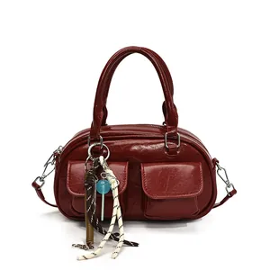 Elegant burgundy boston pillow bag with silver buckles and decorative charm on white background